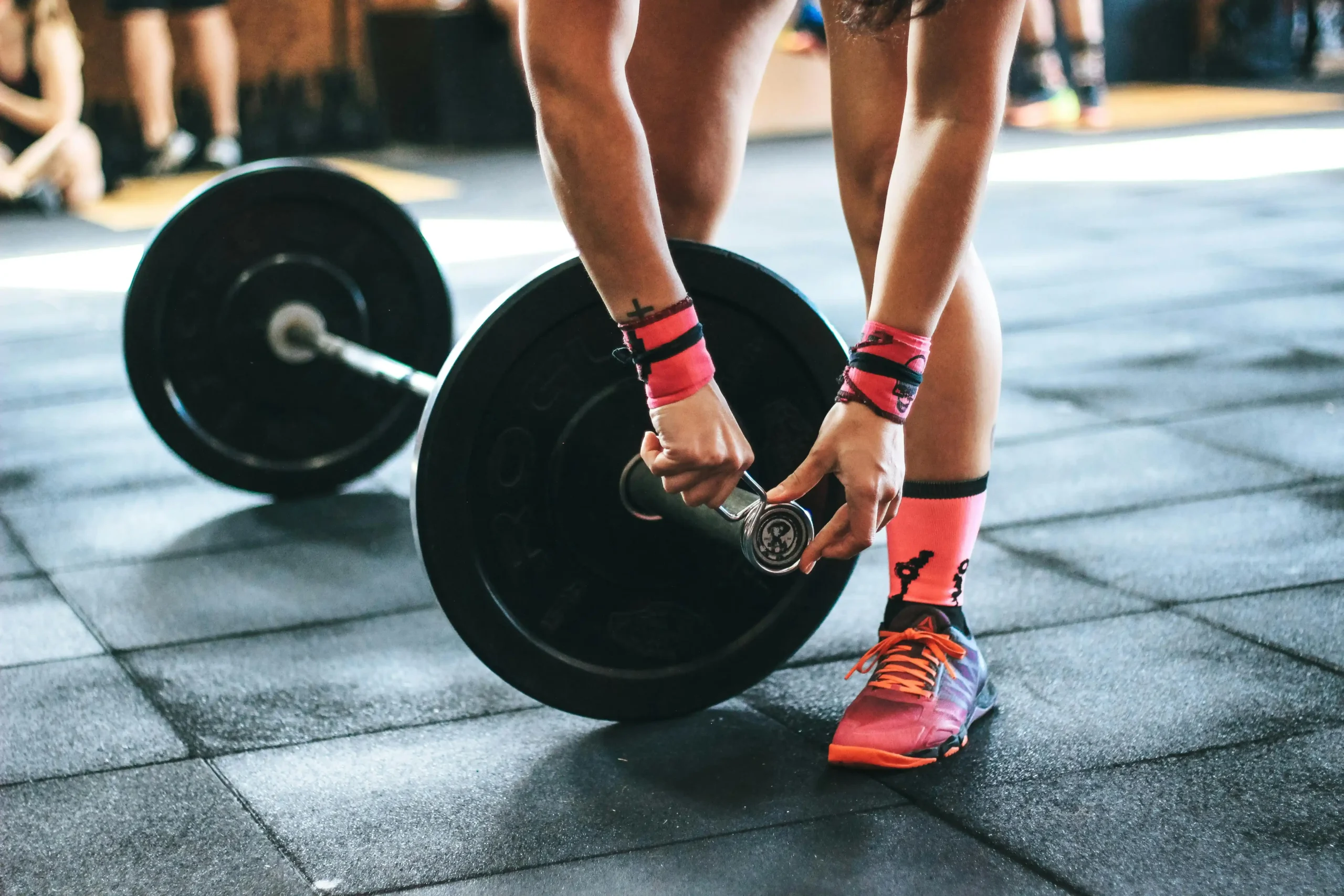 cross trainning-edumouv Une femme soulève une barre de musculation dans une salle de sport.